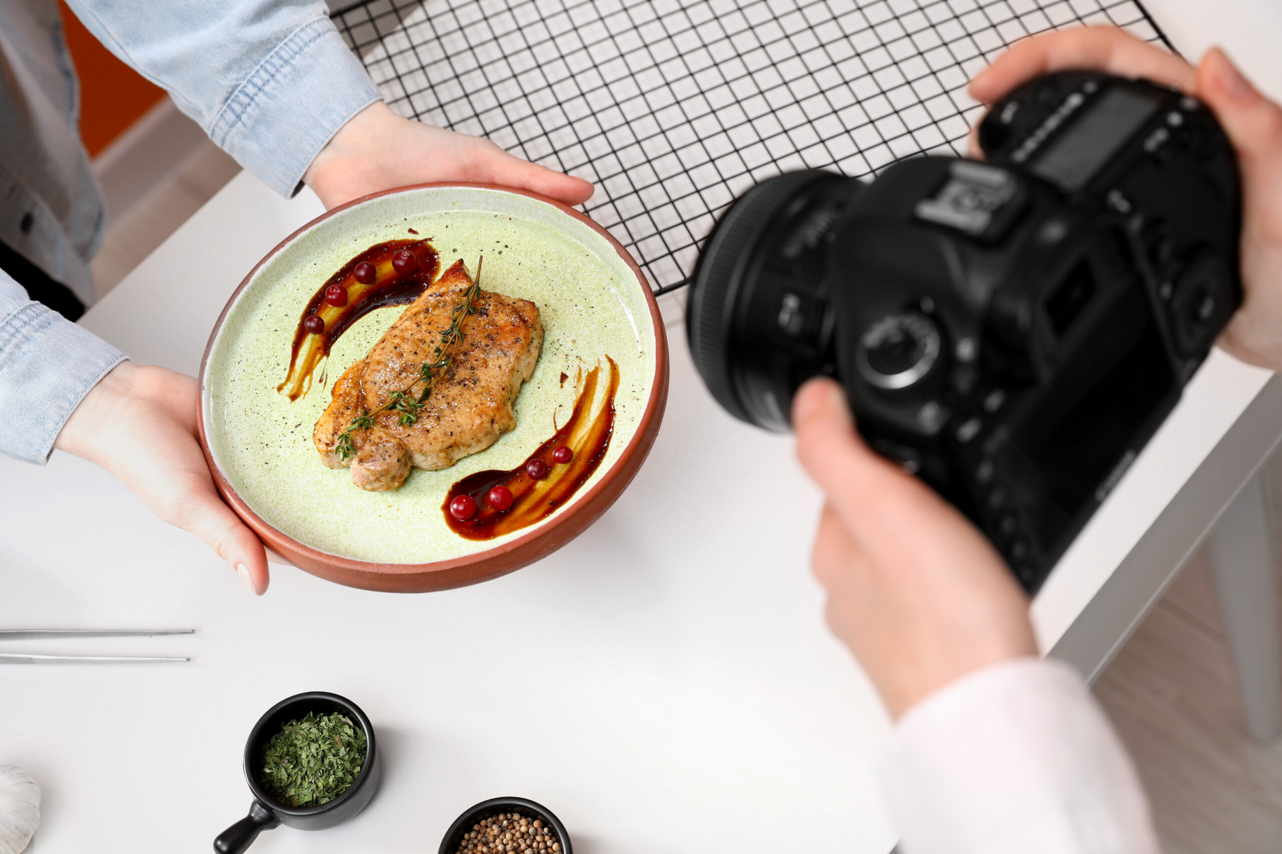 Food stylist holding plate with delicious meat medallion while p