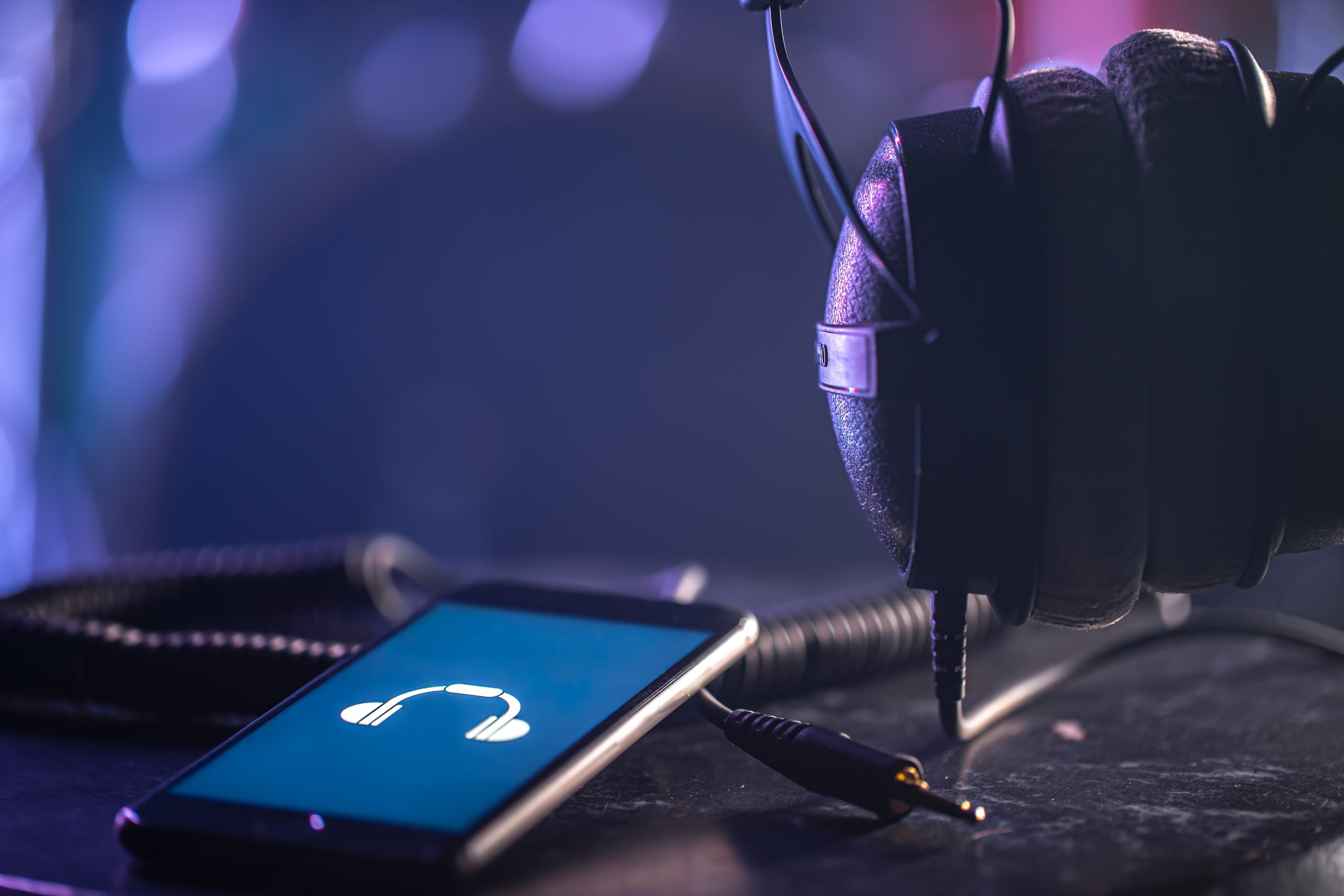 Musical background with a phone and headphones on a dark background.