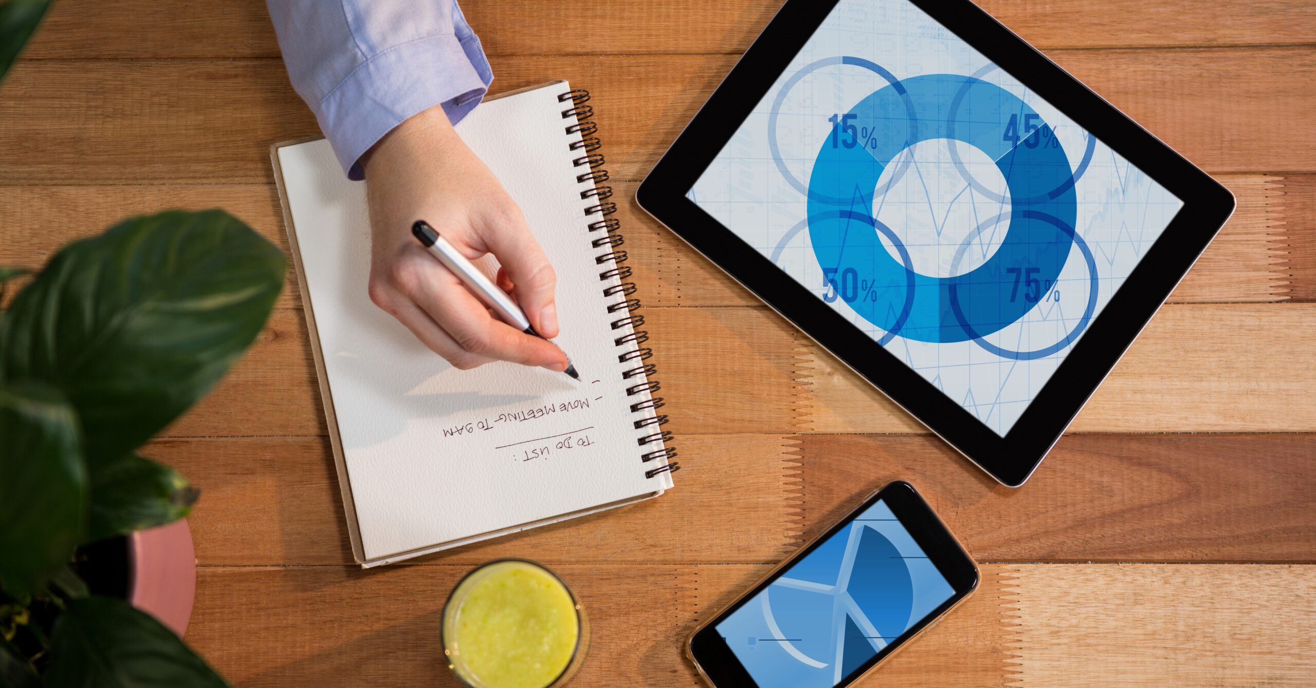 Digital tablet and mobile phone on table with hand writing on notebook